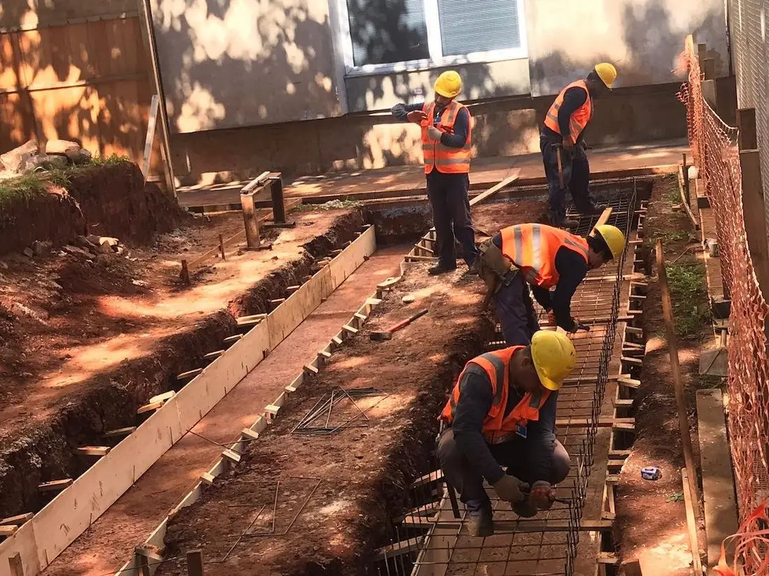 Operarios con casco y chaleco armando las fundaciones de una obra