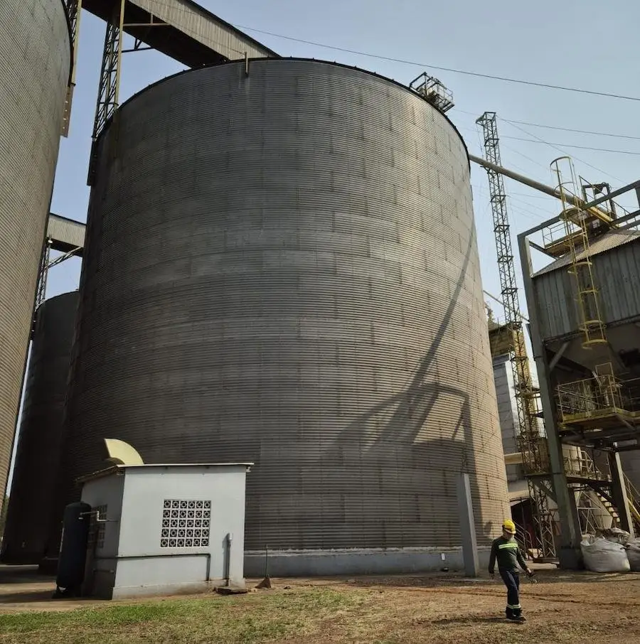 Operario caminando junto a un silo de gran tamaño en una planta de acopio